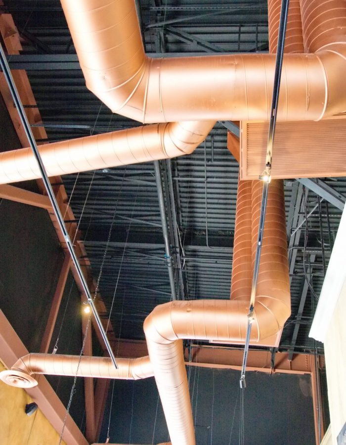 Copper ductwork running under a black metal ceiling