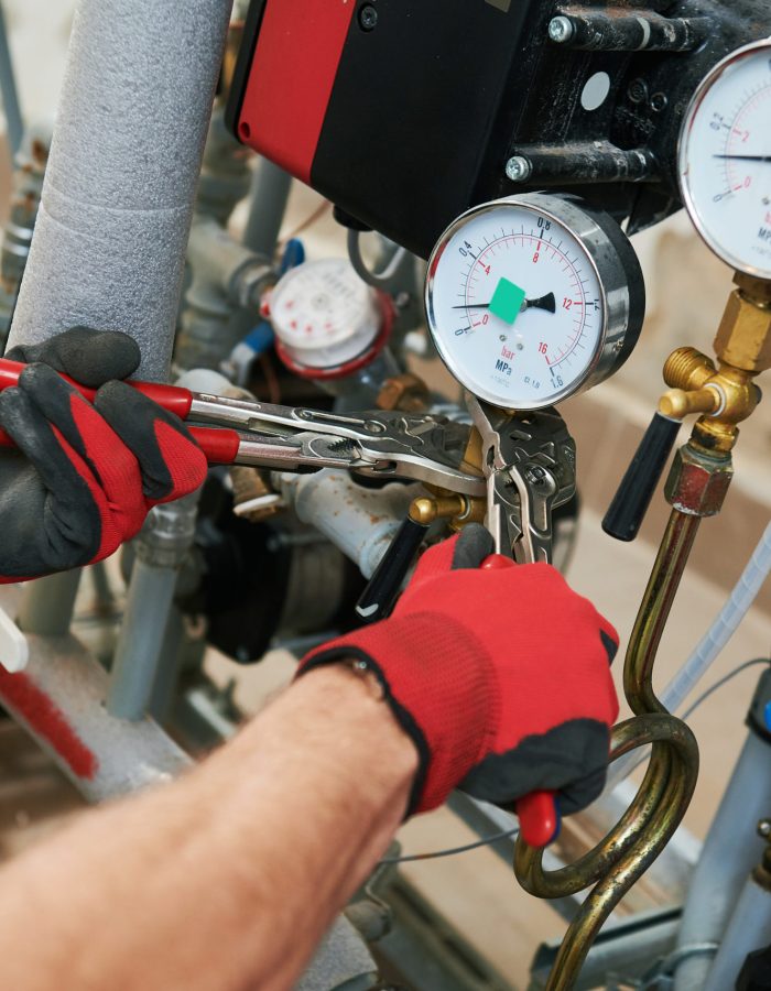 heating engineer or plumber in boiler room installing pipeline manometer